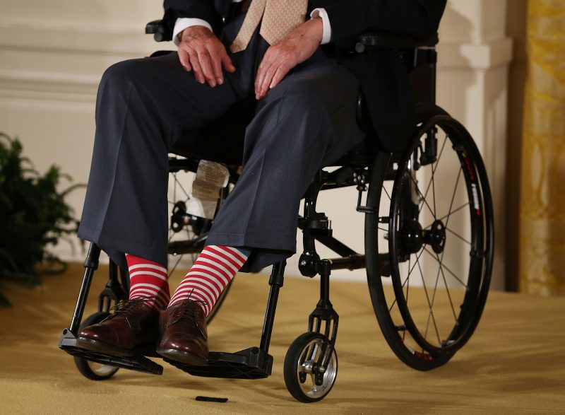 Former President George H. W. Bush wears red stripped socks as he sits in a wheelchair during an event in the East Room at the White House, on July 15, 2013 in Washington.