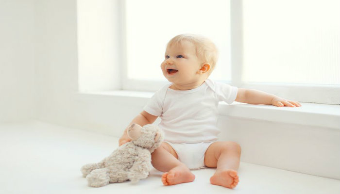 1_Cute-smiling-baby-with-teddy-bear-toy-home-in-room