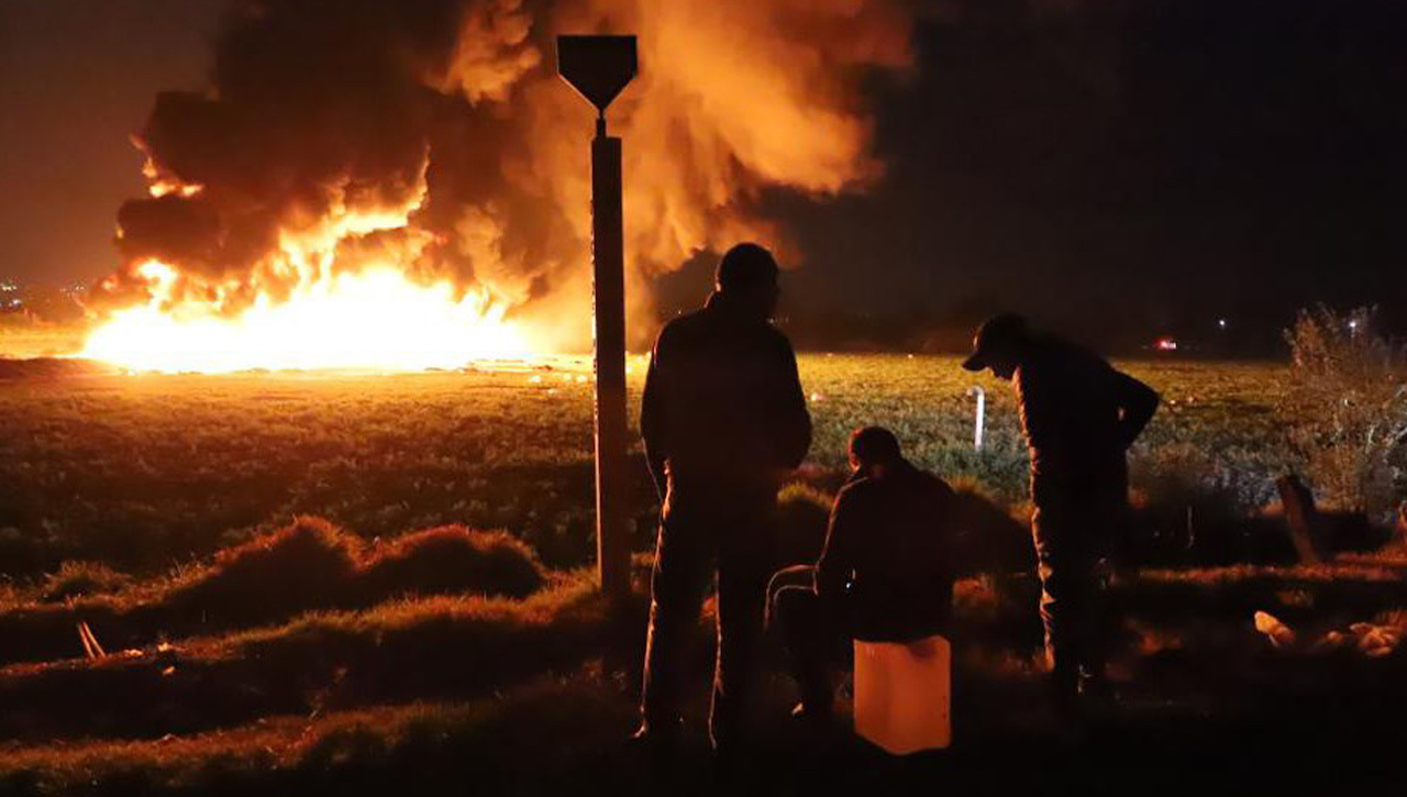 epa07298870 People wait in front of a wall of fire after an explosion of an illegal tap on Mexican oil company Pemex's pipeline in Tlahuilipan, state of Hidalgo, Mexico, late night 18 January 2019. At least 21 people died and 71 other people were wounded in the blast, according to official sources.  EPA-EFE/OASA