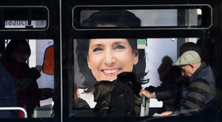 Commuters travel in a bus past an election poster of presidential candidate Salome Zurabishvili in Tbilisi on November 27, 2018, on the eve of the second round of presidential elections. (Photo by Vano Shlamov / AFP)        (Photo credit should read VANO SHLAMOV/AFP/Getty Images)