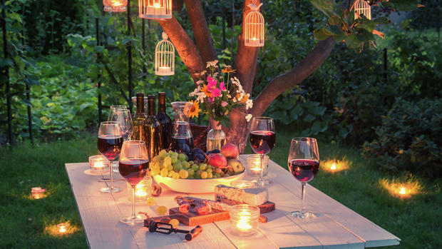 Beautiful table full of cheese and meats in garden at dusk