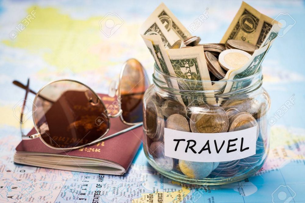 Travel budget concept. Travel money savings in a glass jar with passport and sunglasses on world map