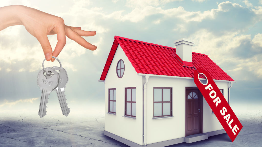 House for sale with hand holding keys on blue sky background
