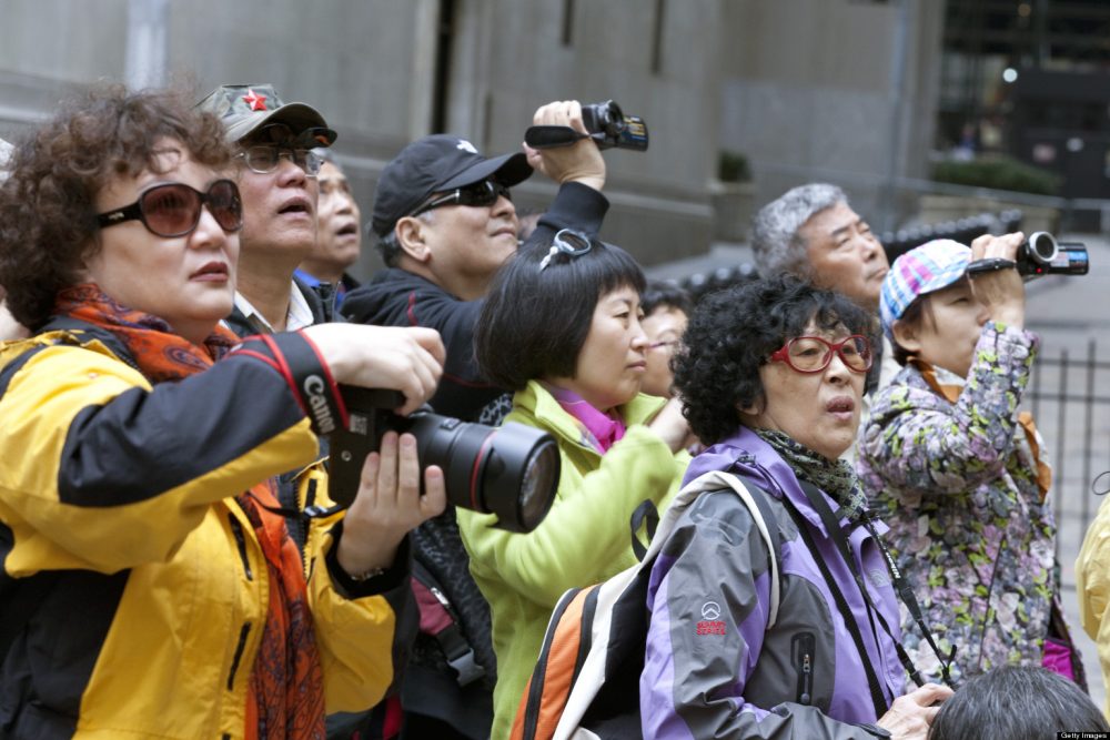 NEW YORK, NY - APRIL 11: Chinese tourists take photos on Wall Street near the New York Stock Exchange, NYSE, on April 11, 2013 in New York, New York. The growing affluence and openness in China allows the Chinese to travel. New York is a popular destination for Americans and foreigners. (Photo by Melanie Stetson Freeman/The Christian Science Monitor via Getty Images)