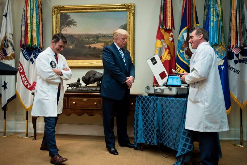 US President Donald Trump (C) and his White House physician Dr. Ronny Jackson (L) listen as US Secretary of Veterans Affairs David J. Shulkin speaks about new technology used by the Department of Veterans Affairs during an event in the Roosevelt Room of the White House August 3, 2017 in Washington, DC. / AFP PHOTO / Brendan Smialowski        (Photo credit should read BRENDAN SMIALOWSKI/AFP via Getty Images)