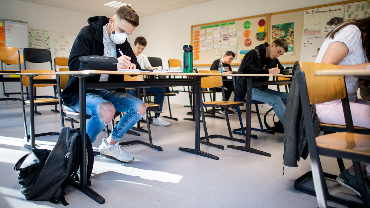 23 April 2020, North Rhine-Westphalia, Übach-Palenberg: Pupils, one of them wearing a protective mask, work on computer science tasks in the basic computer science course of the Abitur year at the Carolus-Magnus-Gymnasium. Barely six weeks after the closure of day-care centres and schools due to corona infections in North Rhine-Westphalia, the schools will reopen on Thursday for exam candidates. Photo: Jonas Güttler/dpa (Photo by Jonas Güttler/picture alliance via Getty Images)