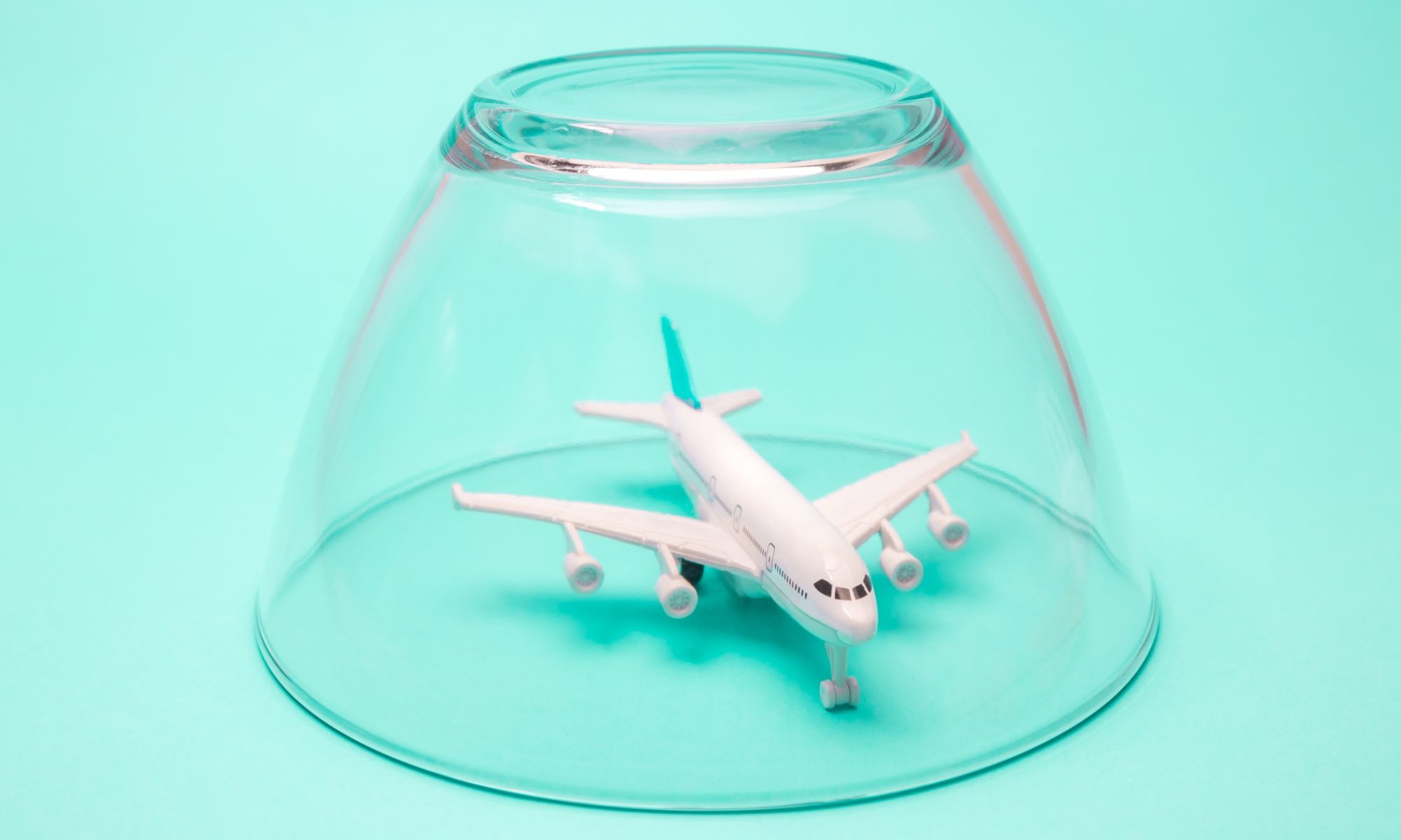 Airplane in isolation quarantine under glass bowl, minimal creative global travel problems during corona virus pandemic.