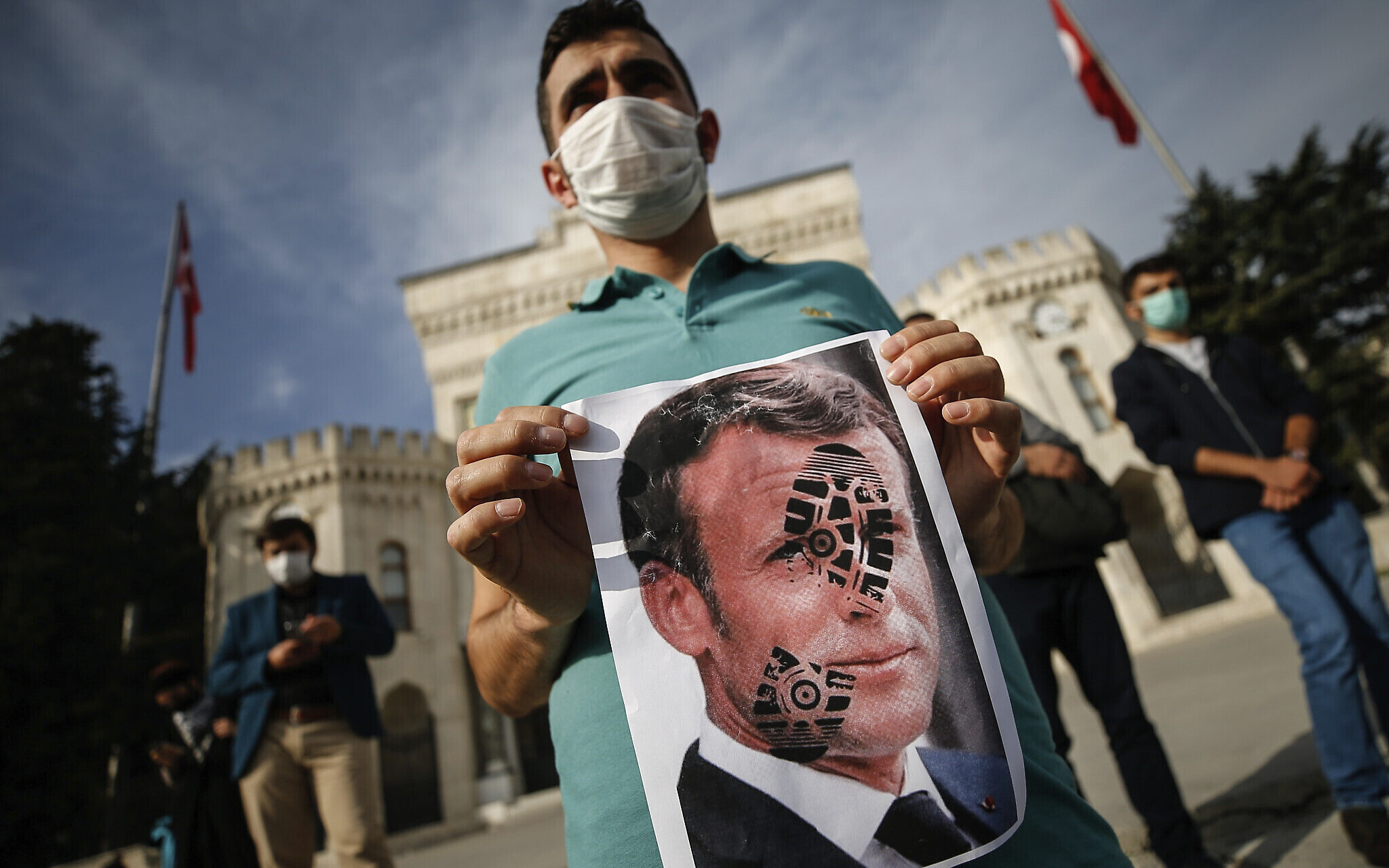 A youth holds a photograph of France's President Emmanuel Macron, stamped with a shoe mark, during a protest against France in Istanbul, Sunday, Oct. 25, 2020. Turkish President Recep Tayyip Erdogan on Sunday challenged the United States to impose sanctions against his country while also launching a second attack on French President Emmanuel Macron. Speaking a day after he suggested Macron needed mental health treatment because of his attitude to Islam and Muslims, which prompted France to recall its ambassador to Ankara, Erdogan took aim at foreign critics. (AP Photo/Emrah Gurel)