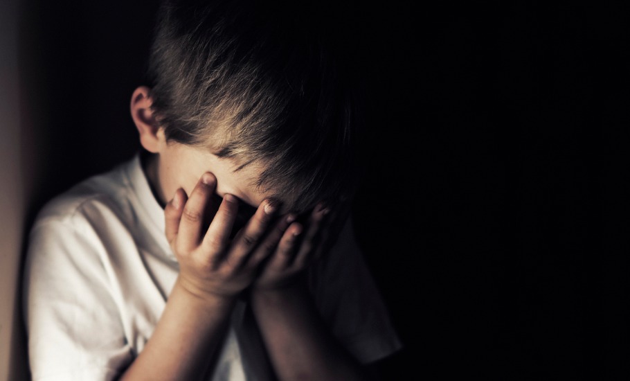 depressed-crying-little-boy-holding-head-in-hands-picture-id637968486