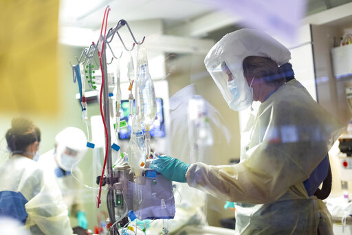 Jack Kingsley R.N. attends to a COVID-19 patient in the Medical Intensive care unit (MICU) at St. Luke's Boise Medical Center in Boise, Idaho on Tuesday, Aug. 31, 2021. St. Luke's Health System announced on Tuesday that it will pause certain elective surgeries and procedures starting Sept. 1 because of increasing COVID-19 cases in Idaho.   (AP Photo/Kyle Green)