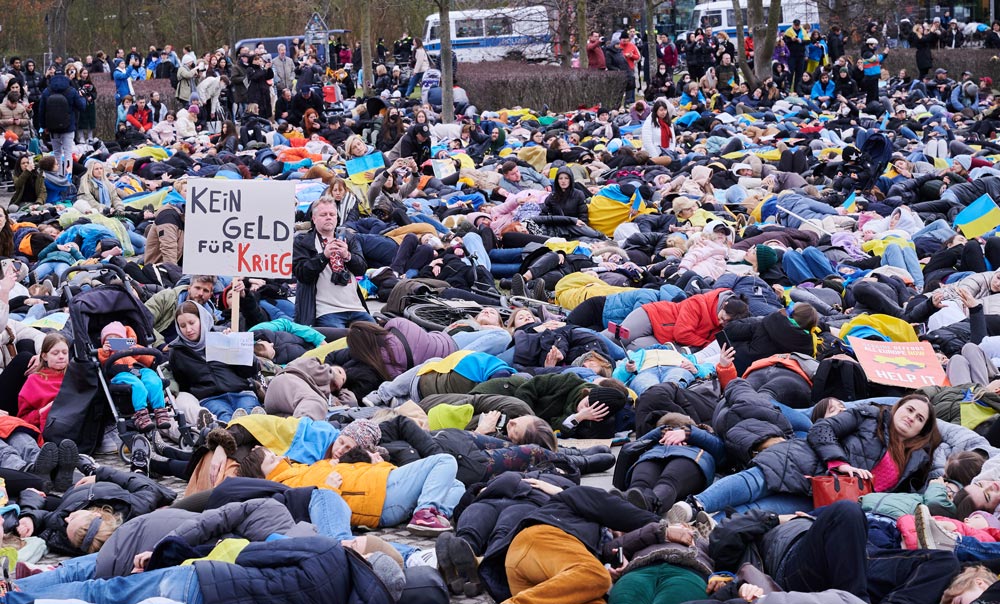 06 April 2022, Berlin: Demonstrators lie on the lawn in front of the Reichstag building during a demonstration against the attack on Ukraine and for an energy embargo against Russia. Photo: Annette Riedl/dpa