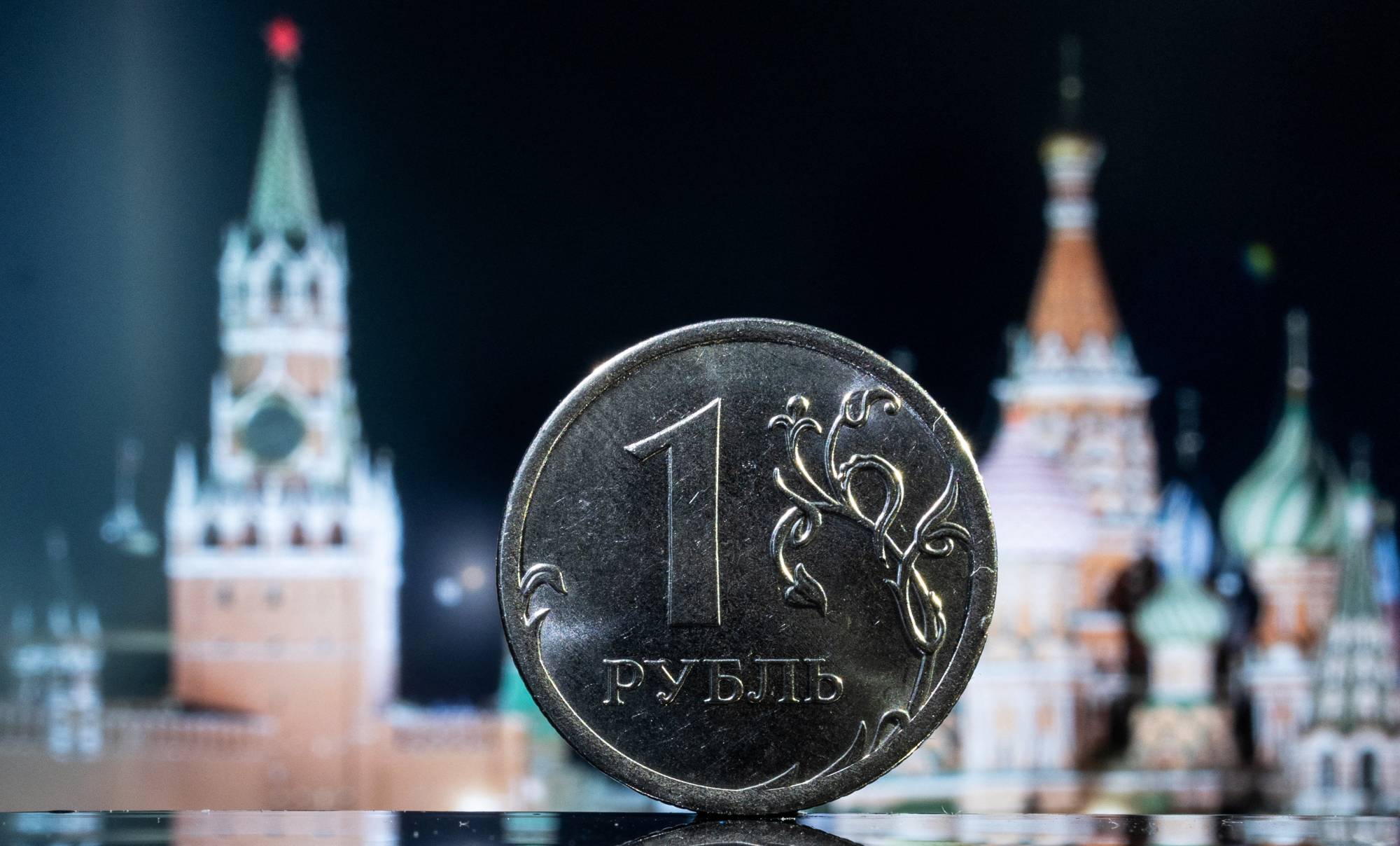 A Russian one rouble coin is pictured in front of a monitor showing St. Basil's Cathedral and a tower of Moscow's Kremlin in this illustration taken June 24, 2022. REUTERS/Maxim Shemetov/Illustration