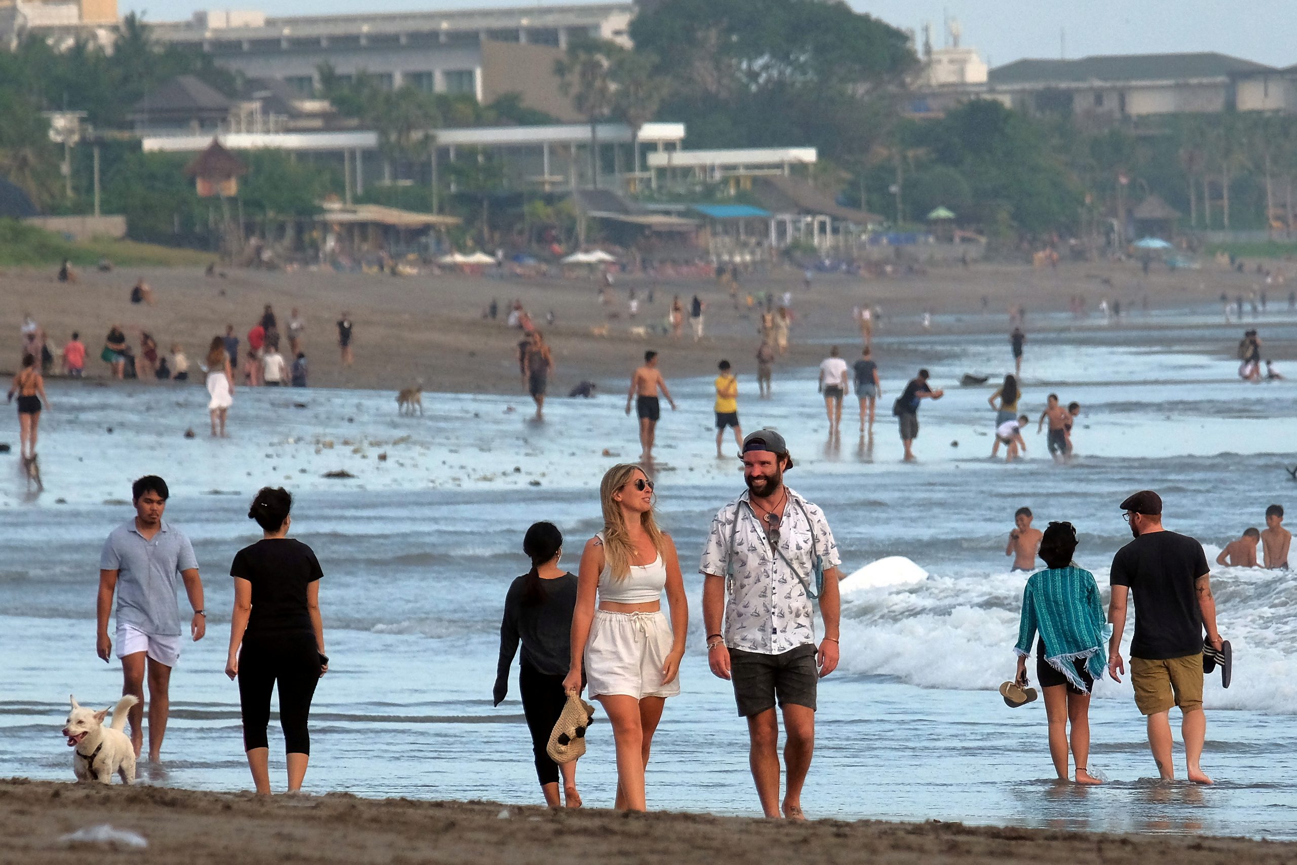 FILE PHOTO: Tourists walk on a beach as the government extends restrictions to curb the spread of coronavirus disease (COVID-19) in Badung, Bali, Indonesia September 9, 2021. Antara Foto/Nyoman Hendra Wibowo/via REUTERS