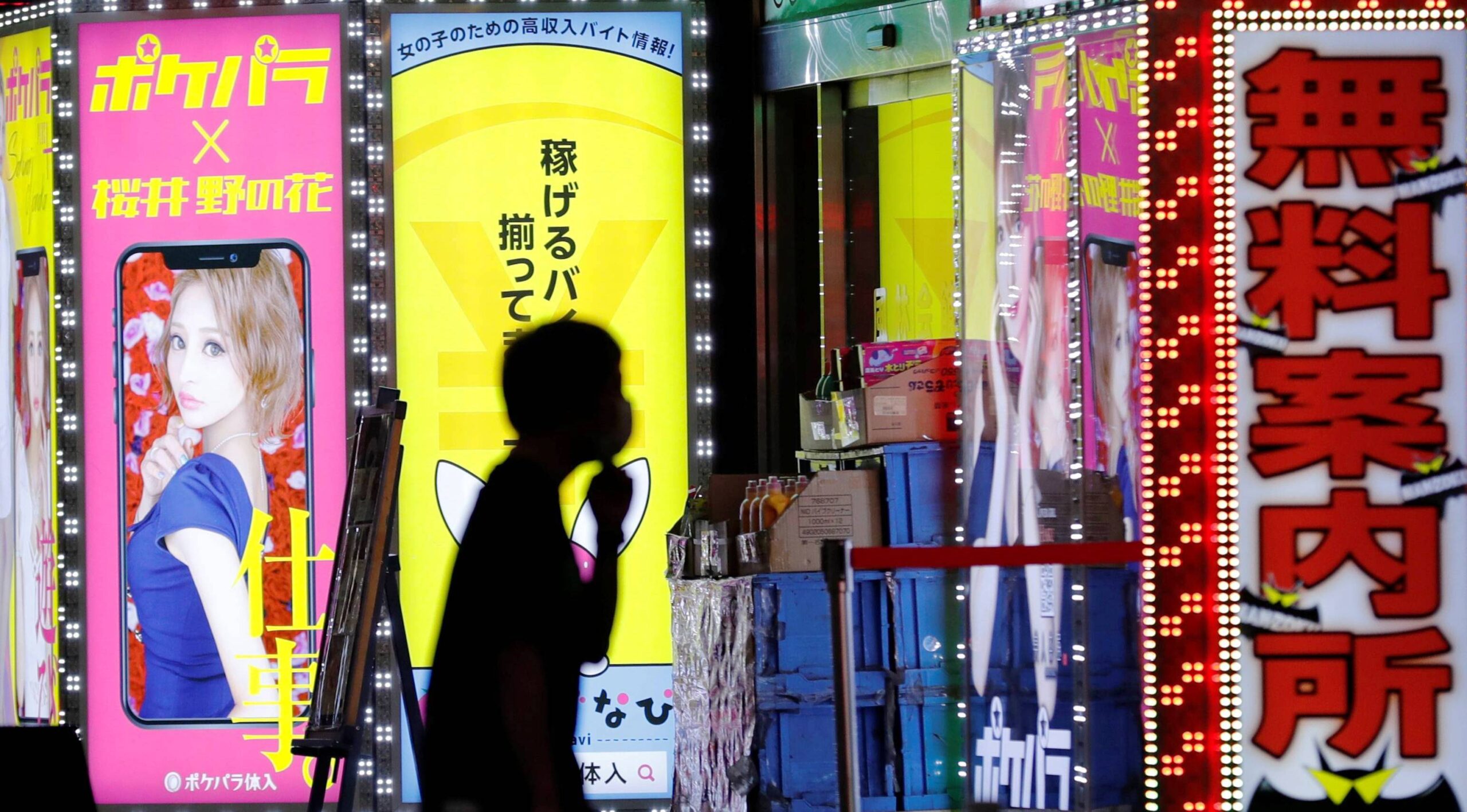 A man wearing a face mask walks past a signboard of a bar in the Kabukicho district, amid the coronavirus disease (COVID-19) outbreak in Tokyo, Japan, July 14, 2020. REUTERS/Kim Kyung-Hoon